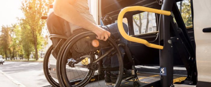 A man in a wheelchair on a lift of a vehicle for people with disabilities.